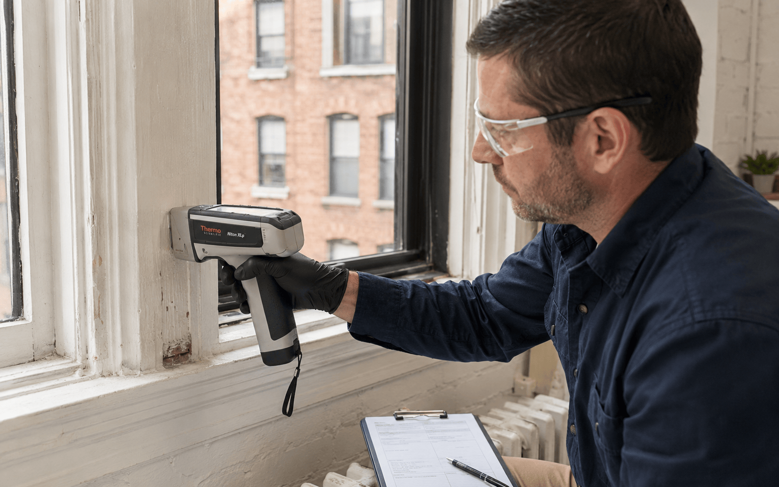Thermo Scientific Niton XLp handheld XRF analyzer inspecting painted NYC apartment window trim for lead paint.